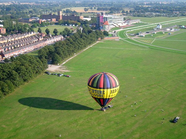 After the inflation of the hot air ballon the balloon, which stands over 100 feet high is heated a little more and eventually reaches equilibrium where it is hovering on the ground. A few more puffs on the hot air burner and the balloon will gently rise away with a sensation not of rising but of the ground slowly dropping away, so stable is the balloon basket on a balloon ride. Here we are taking off from the Knavesmire as it is popularly know, just a mile south of York city centre.